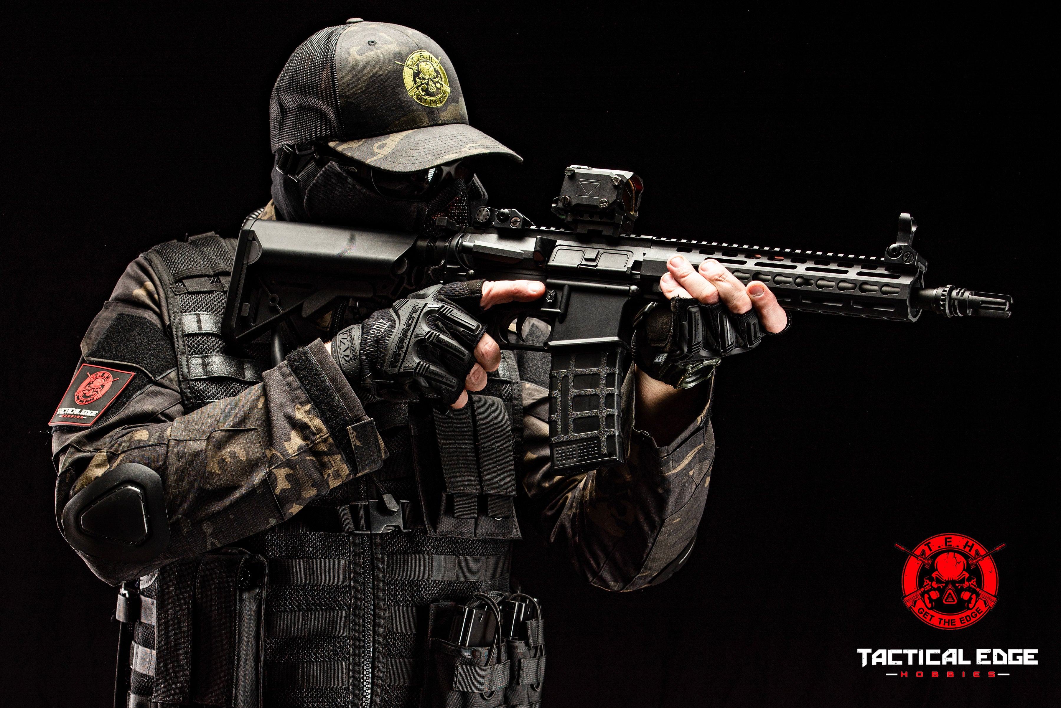 Person in tactical gear holding a rifle with a black background