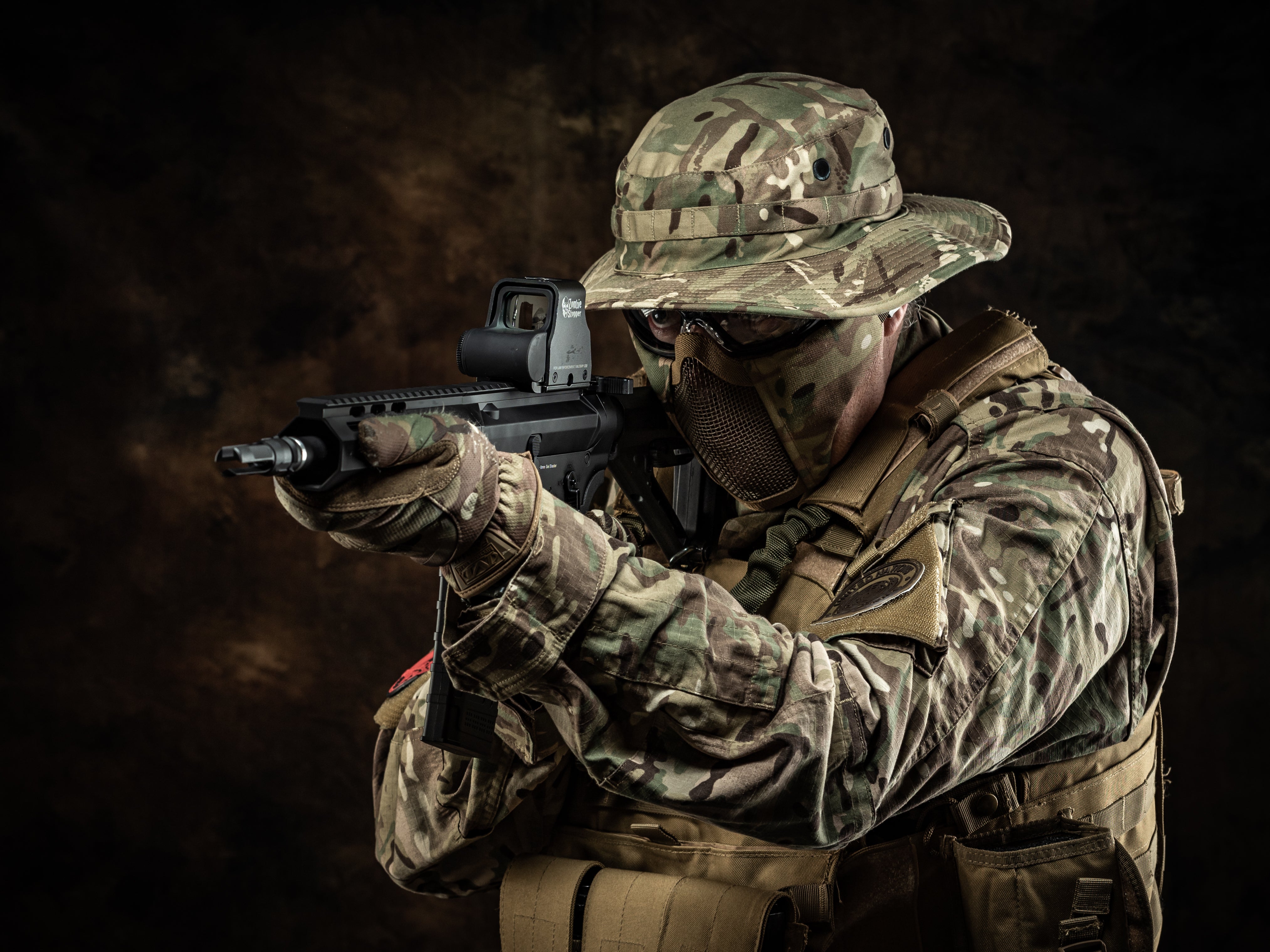 Person in military gear holding a gel blaster gelsoft electric rifle against a dark background